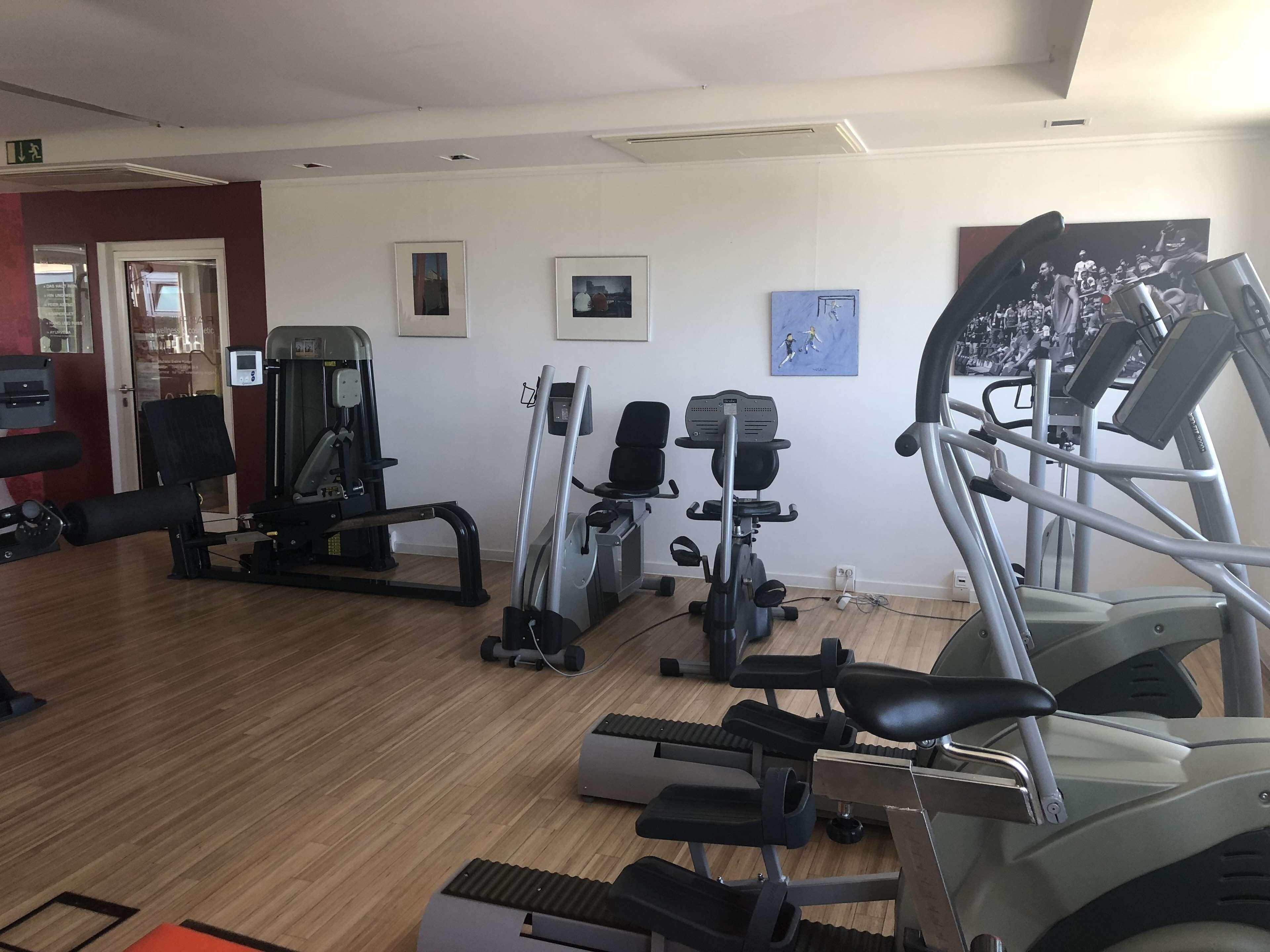 Een sportschool met diverse fitnessapparaten, waaronder loopbanden en krachttoestellen.