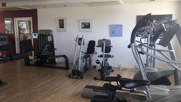 Een sportschool met diverse fitnessapparaten, waaronder loopbanden en krachttoestellen.
