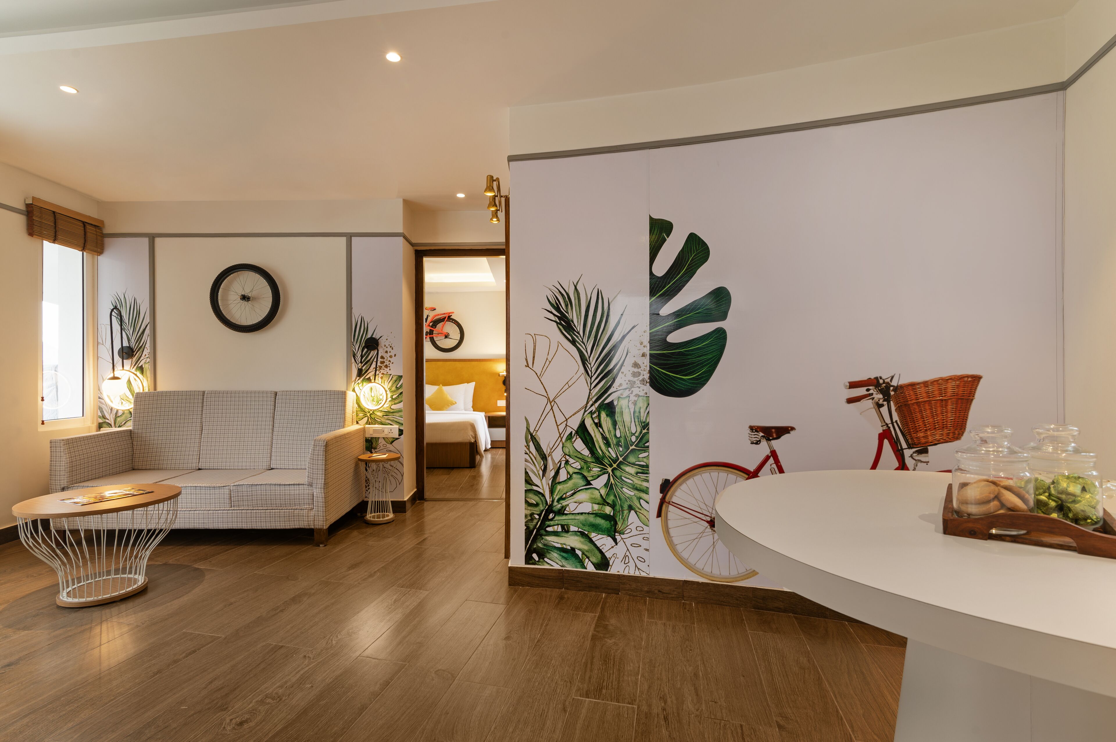 A modern living room with a sofa, a round coffee table, and a wall with a large plant mural.
