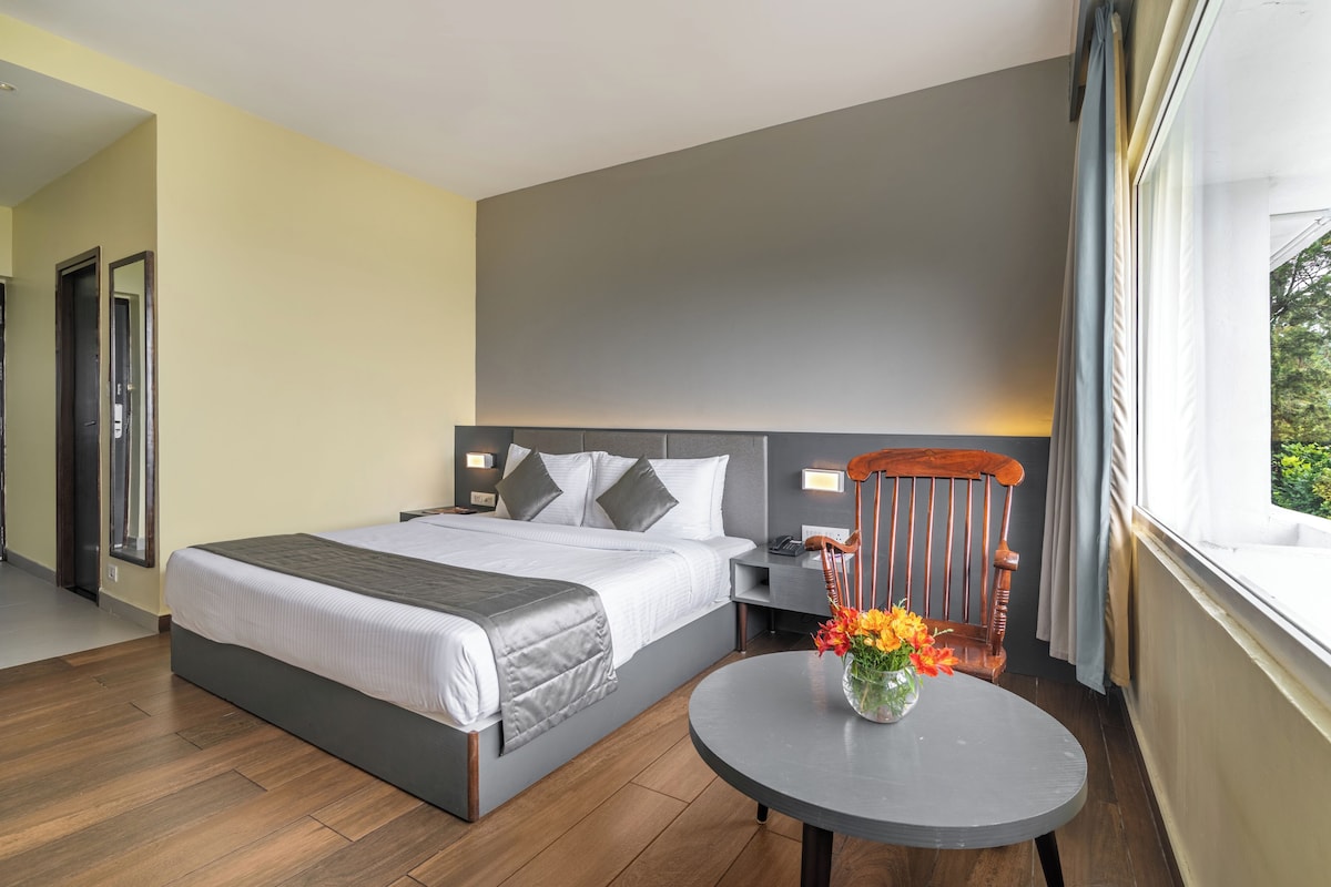 Una habitación de hotel moderna con una cama grande, una mesita de noche y una pequeña mesa redonda con flores.