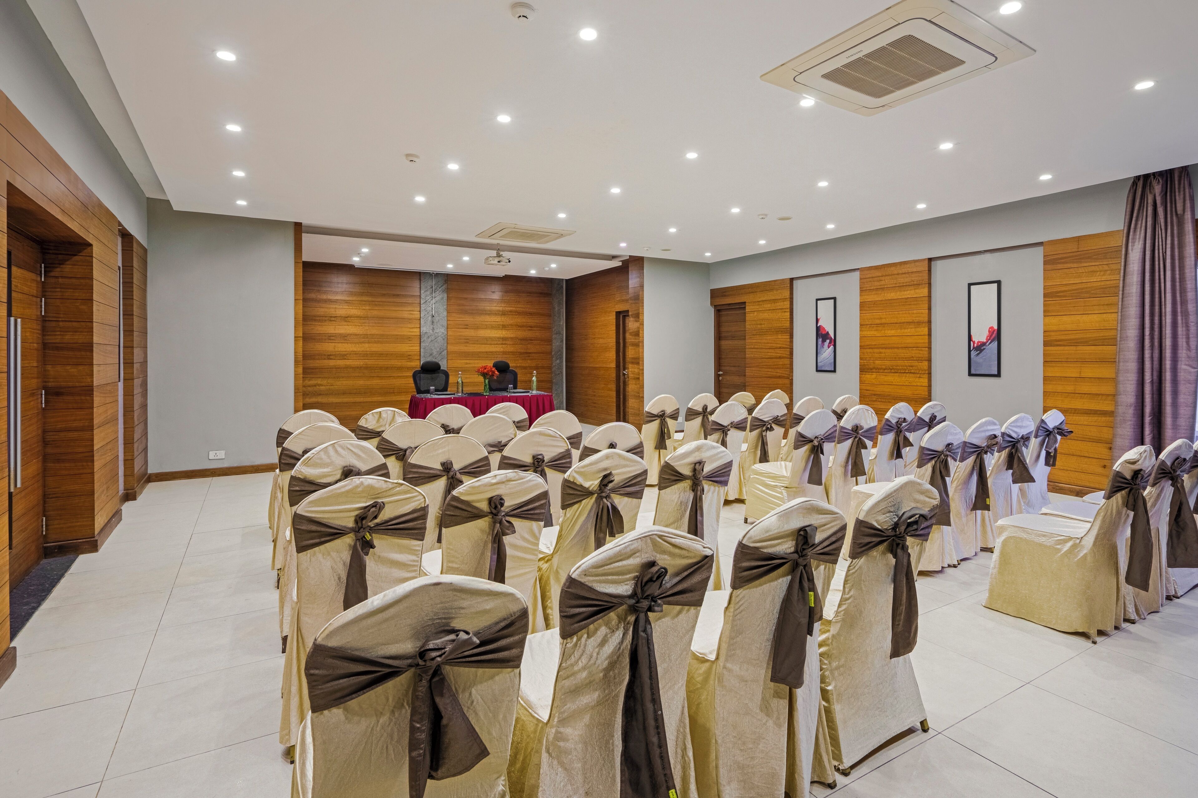 A conference room with rows of chairs, a podium, and wooden paneling on the walls.