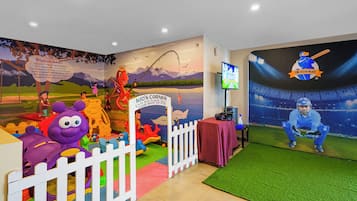 A children's play area with a mural, a white picket fence, and a cricket-themed wall.