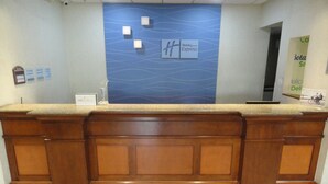 Un mostrador de recepción con un diseño azul ondulado, un cartel de Holiday Inn Express y una barra con una placa.