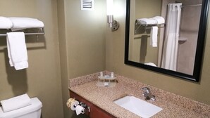 Un baño con inodoro, lavamanos, espejo, toallero y un cubo de basura.