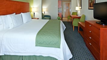 Ein Hotelzimmer mit einem großen Bett, einem Schreibtisch mit Stuhl, einem Fernseher und einer kleinen Küchenzeile.