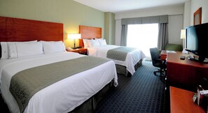 Ein Hotelzimmer mit zwei Betten, einem Schreibtisch mit Computer und einem Fernseher.