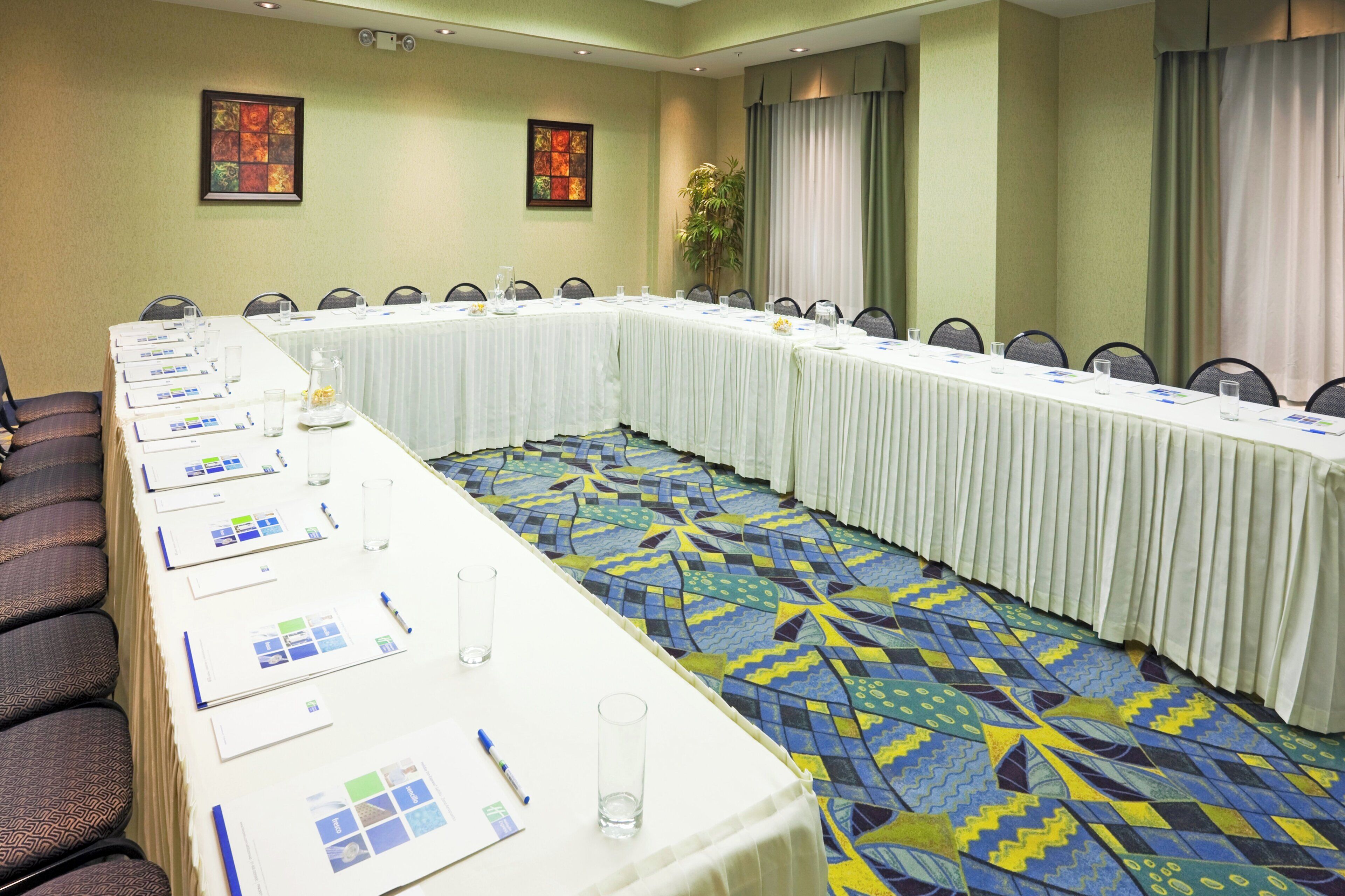 Una sala de conferencias con una mesa larga, sillas y una alfombra estampada.