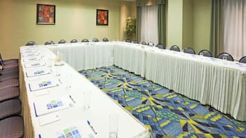 Una sala de conferencias con una mesa larga, sillas y una alfombra estampada.