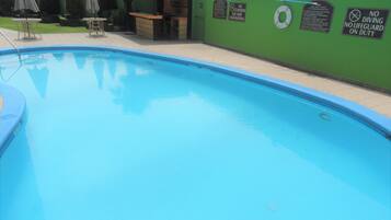 A swimming pool with a lifeguard station, a bar, and several lounge chairs.