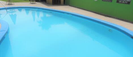 A swimming pool with a lifeguard station, a bar, and several lounge chairs.