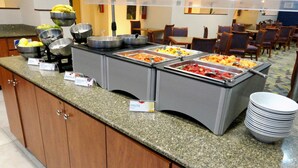 Een buffetgedeelte met containers met labels voor granola, yoghurt en fruit.