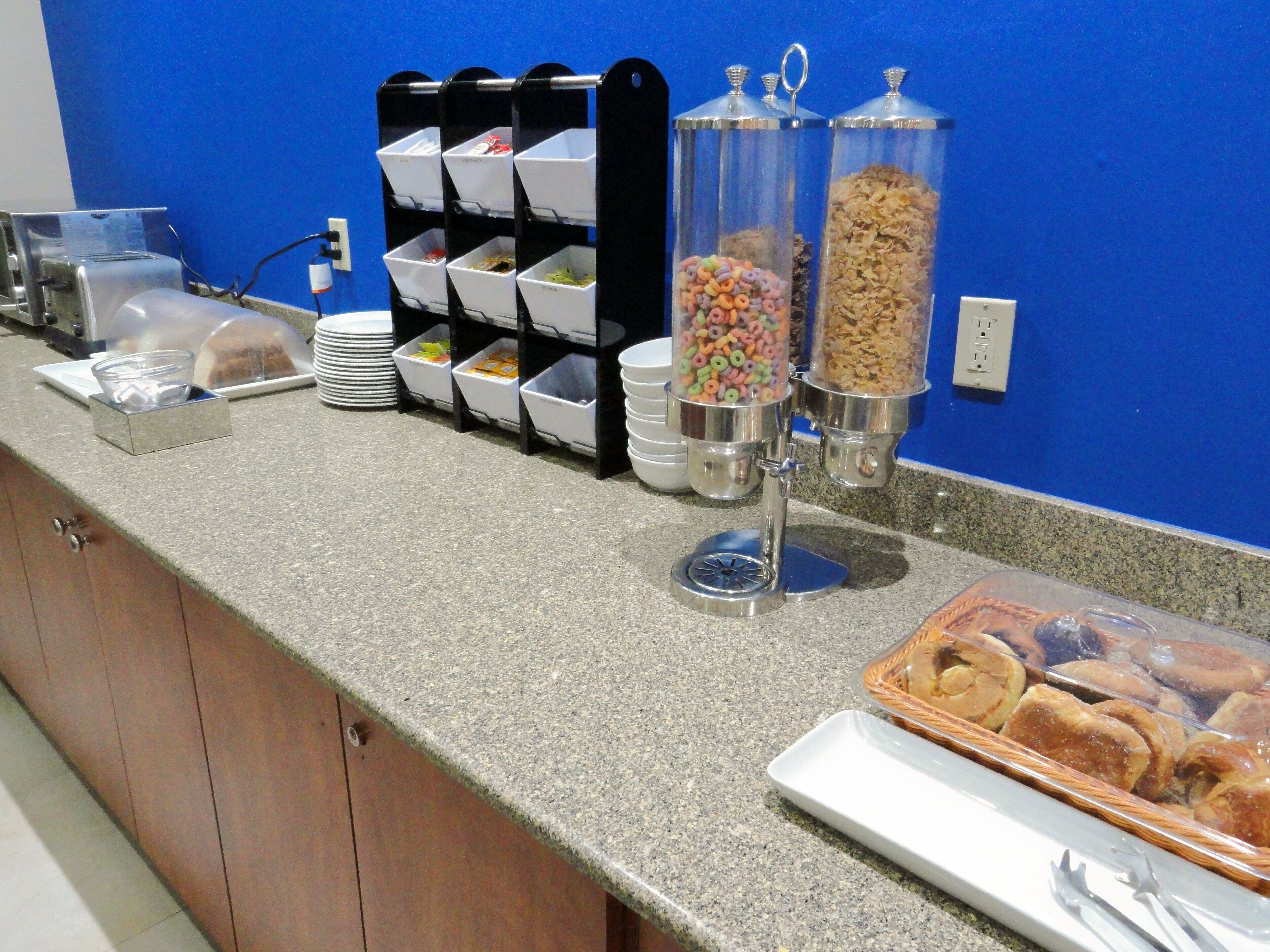 A breakfast buffet with cereal, yogurt, and pastries.
