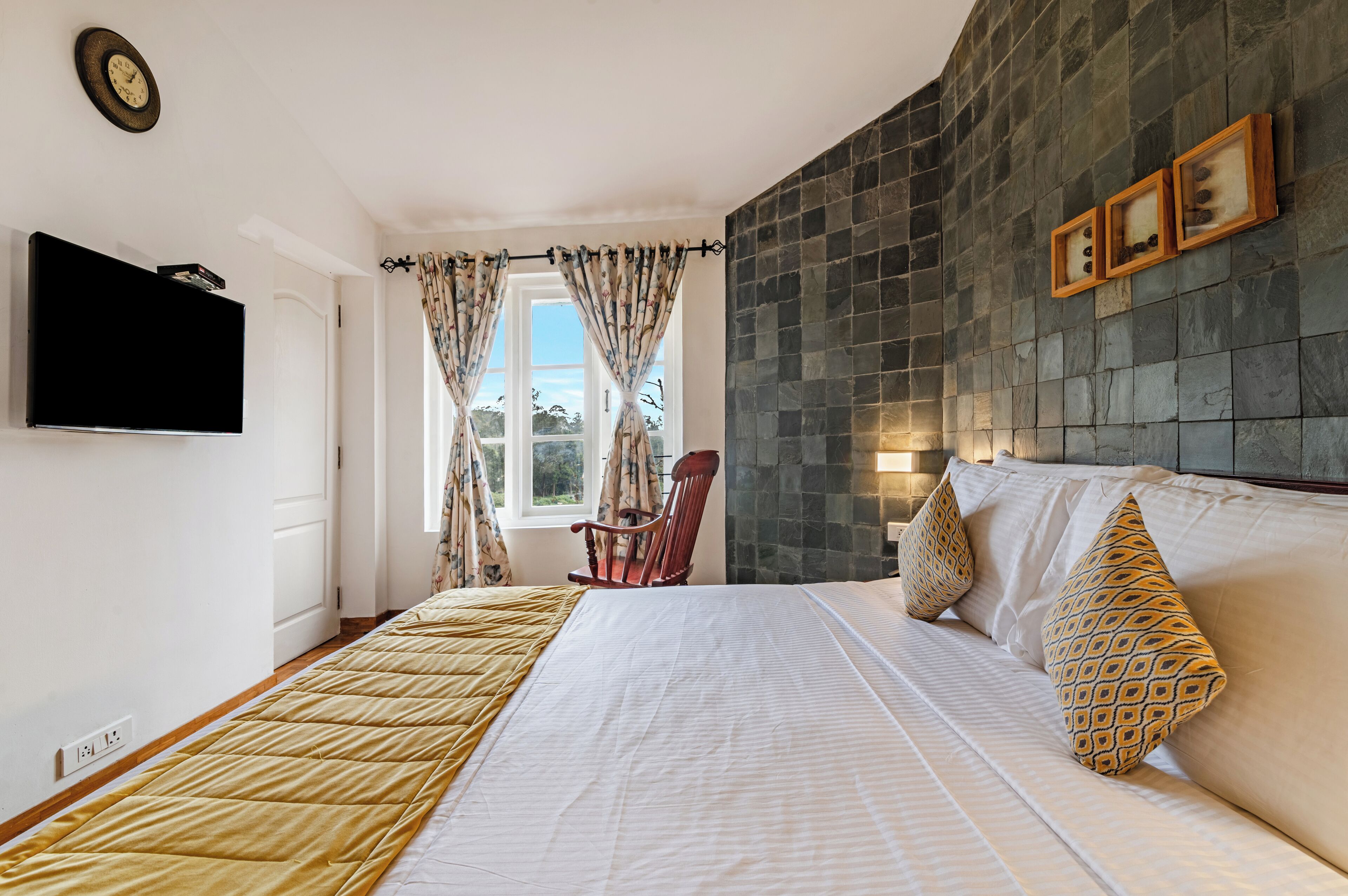 Ein Hotelzimmer mit einem Bett, einem Sessel, einem Fernseher und einer Steinwand.