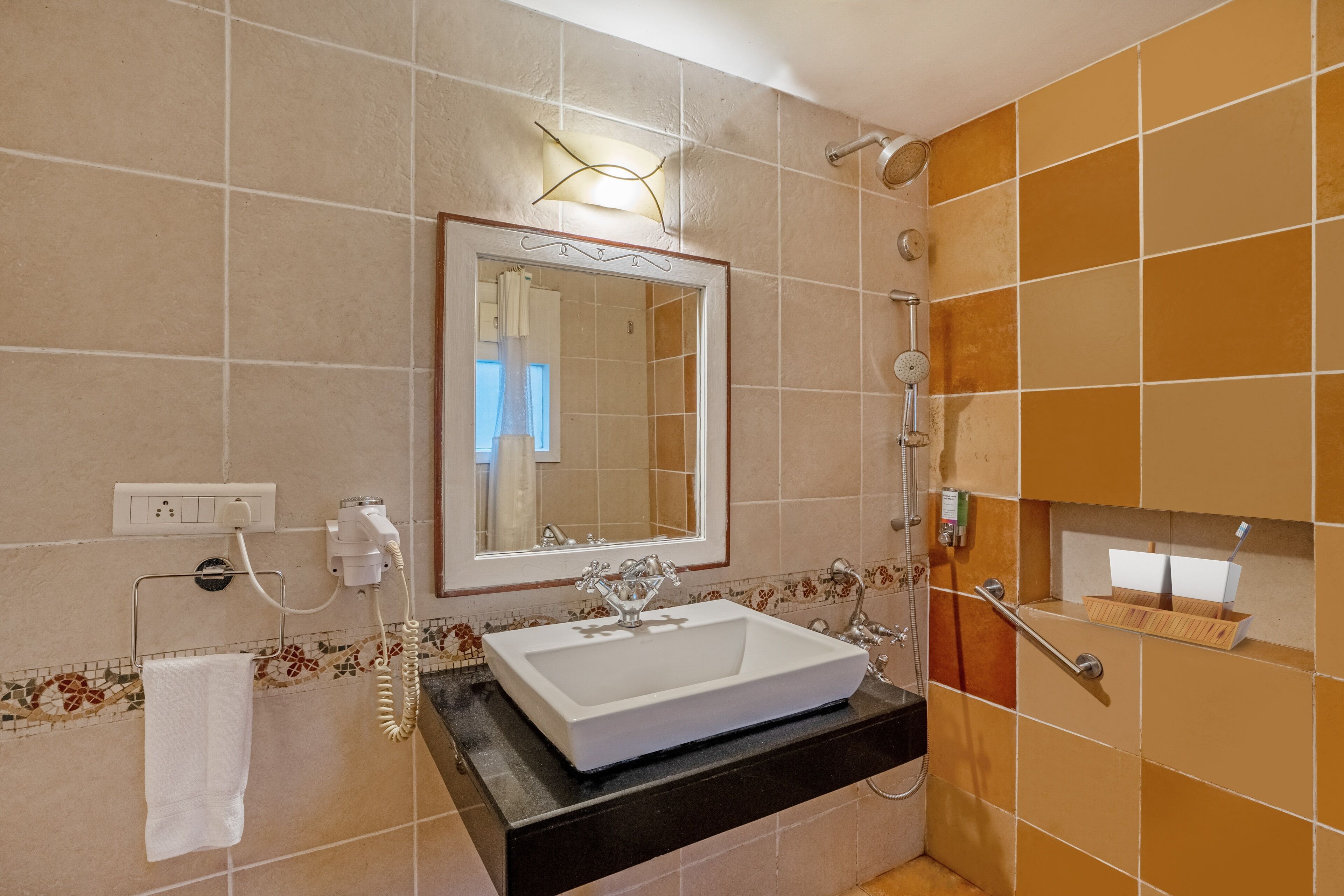 Un baño con lavamanos blanco, un espejo, toallero y zona de ducha.