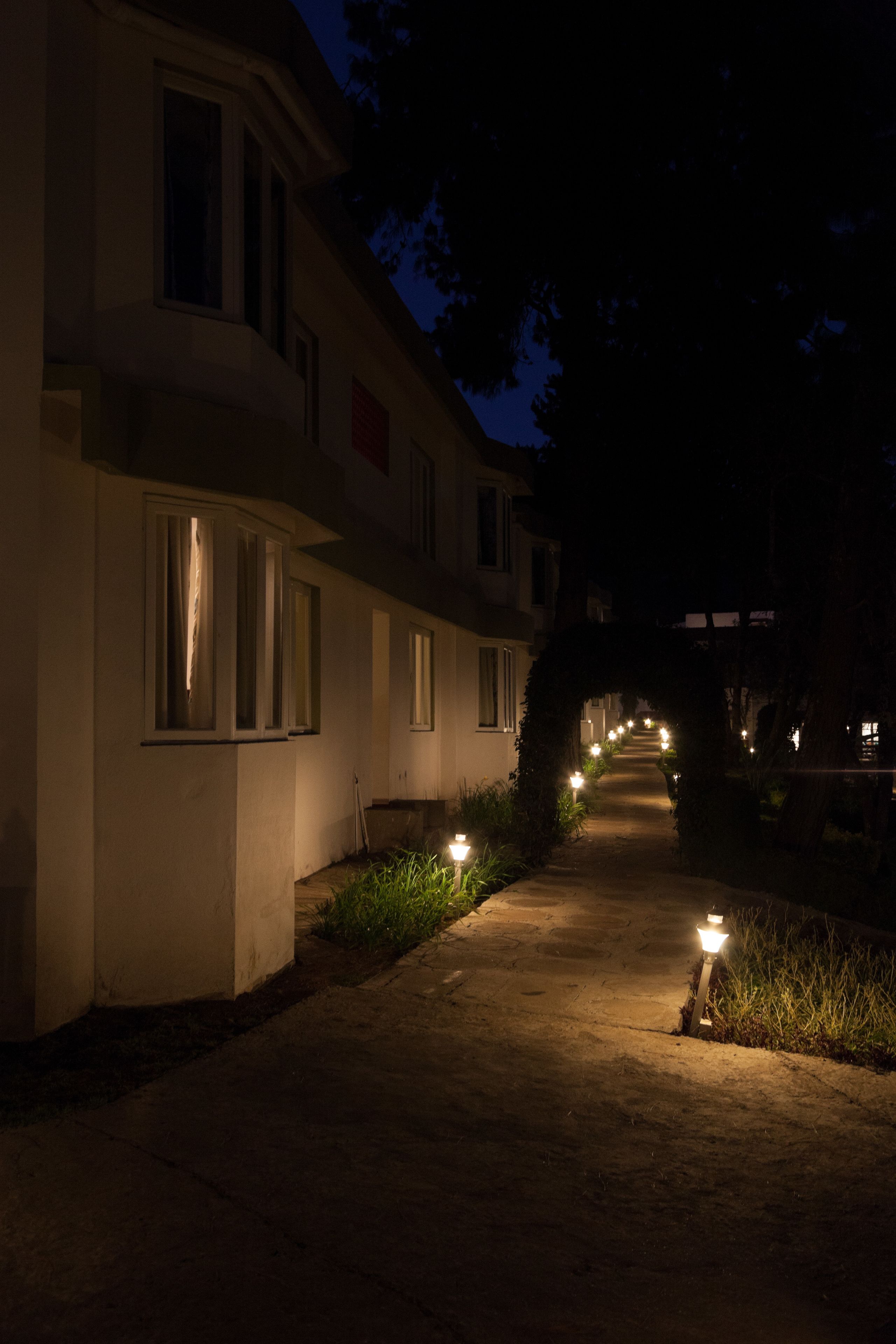 A pathway leading to a building with multiple windows and a covered walkway.