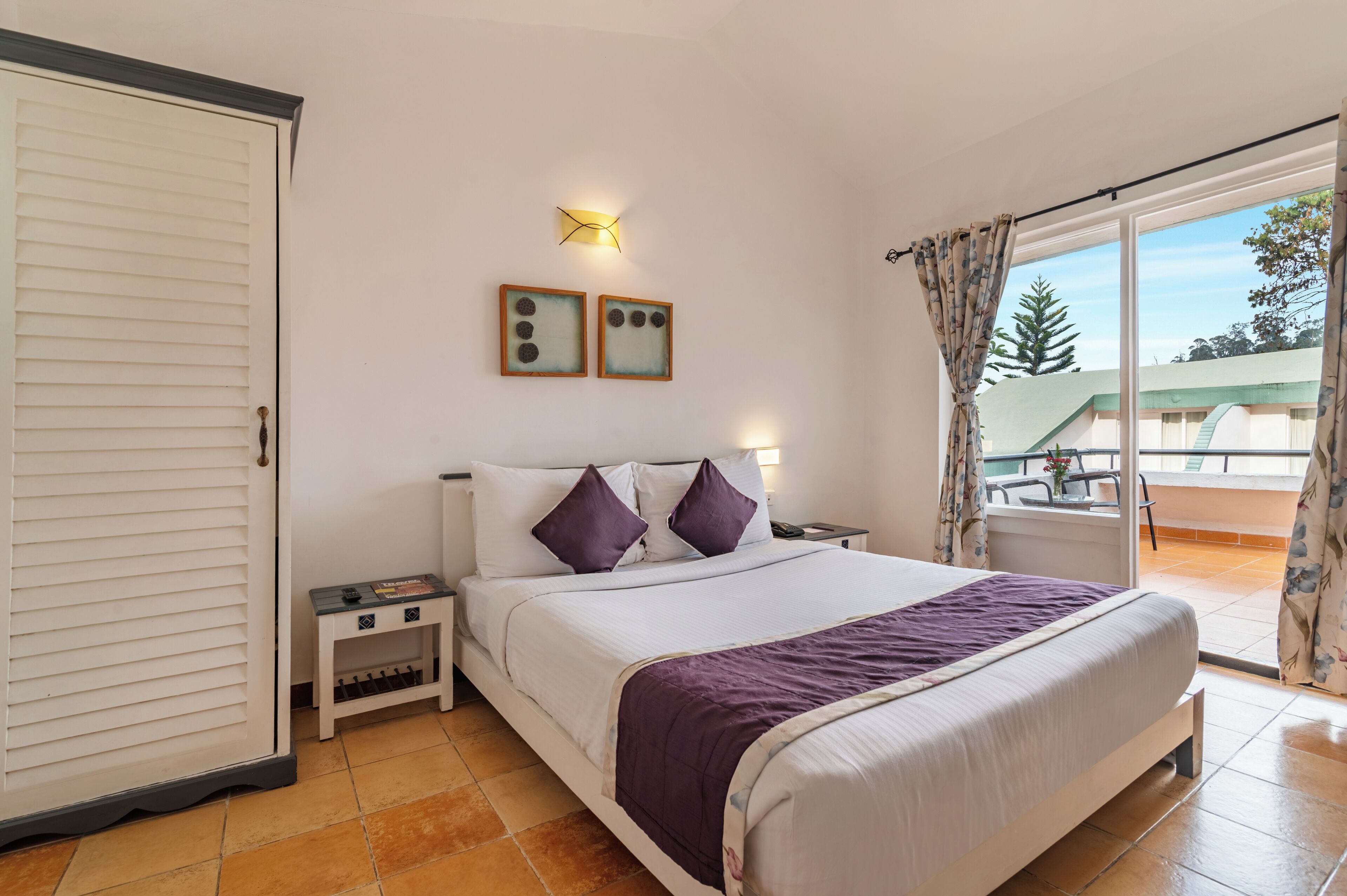 Un dormitorio con cama, mesitas de noche, armario y balcón con vistas.