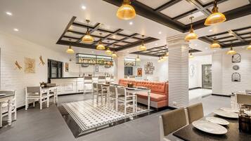 A spacious hotel lobby with a central seating area, a bar, and a reception desk.