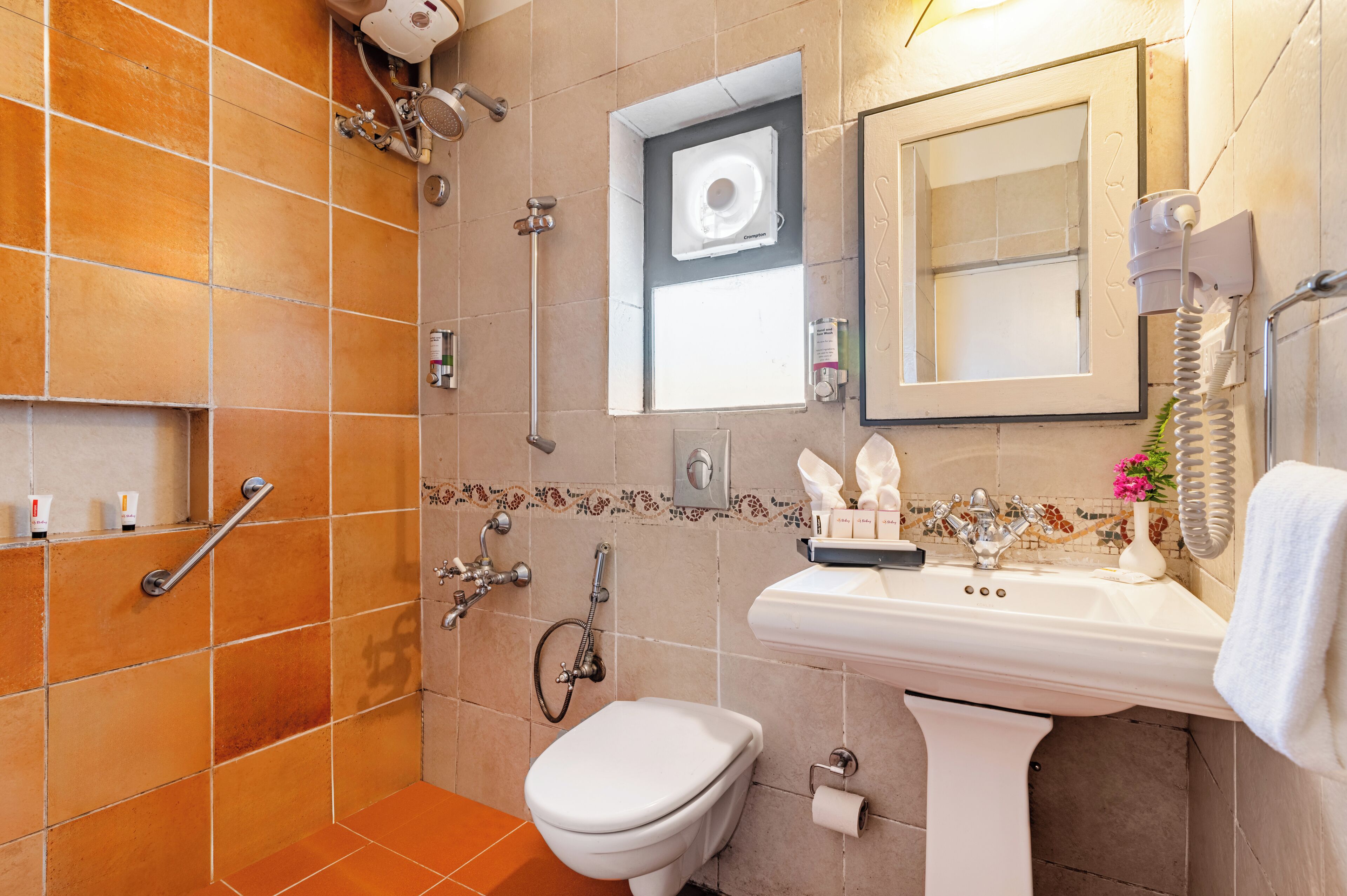 A bathroom with a shower, toilet, sink, and mirror.