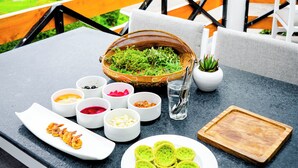 A table set with various dishes, a bowl of greens, and a small potted plant.