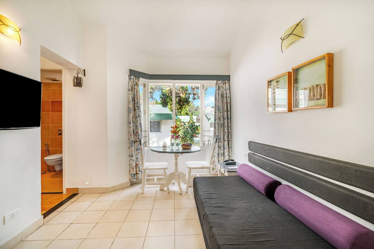 Une chambre moderne avec un canapé, une petite table et une fenêtre avec des rideaux.