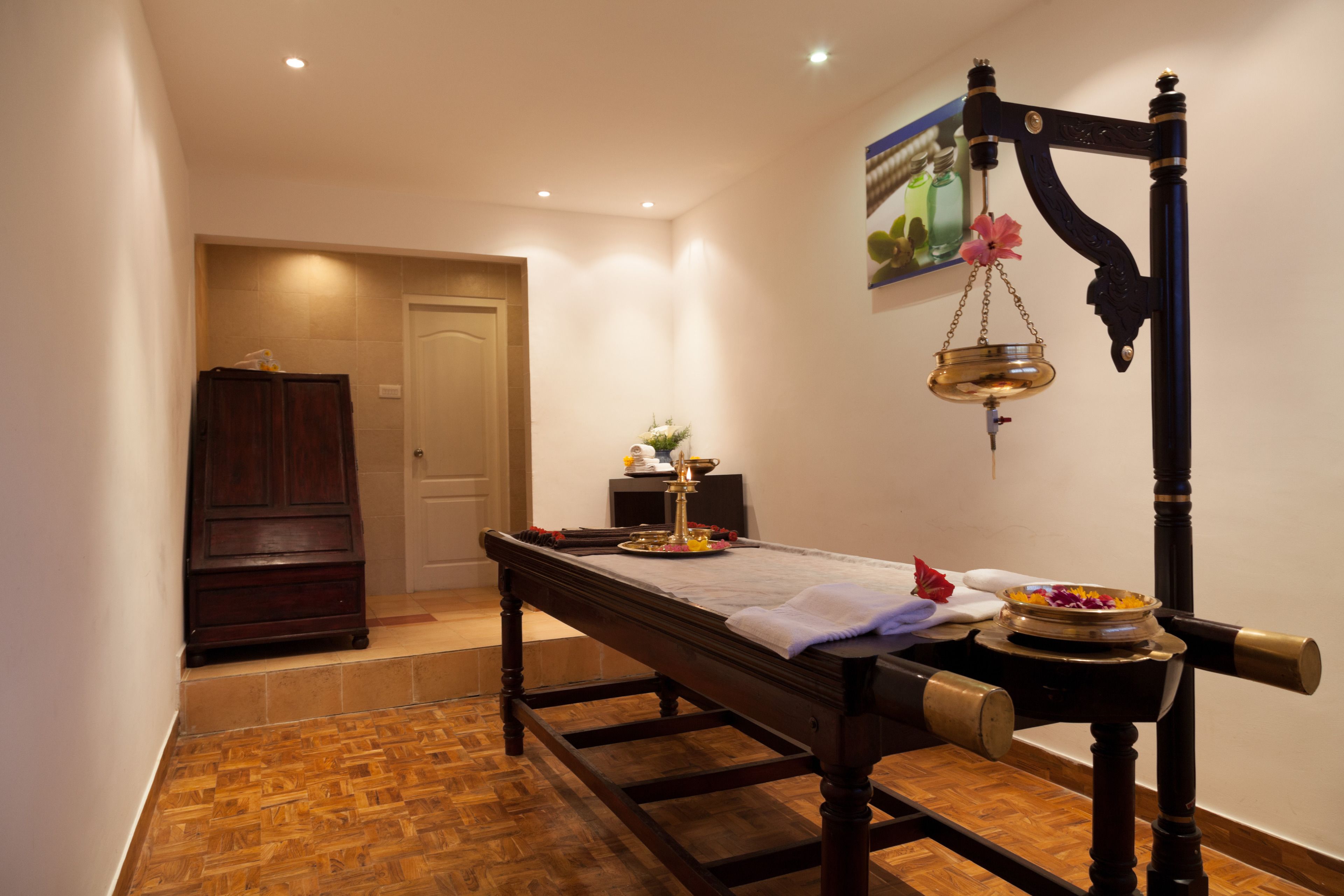 A room with a wooden bench, a small altar with flowers, and a traditional scale on the wall.