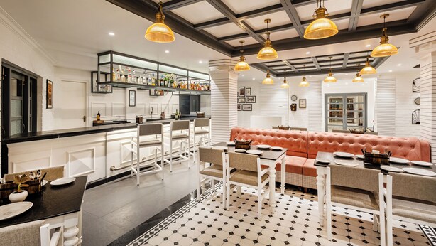 A modern kitchen with white cabinetry, a bar area, and a seating area with a sofa and dining table.