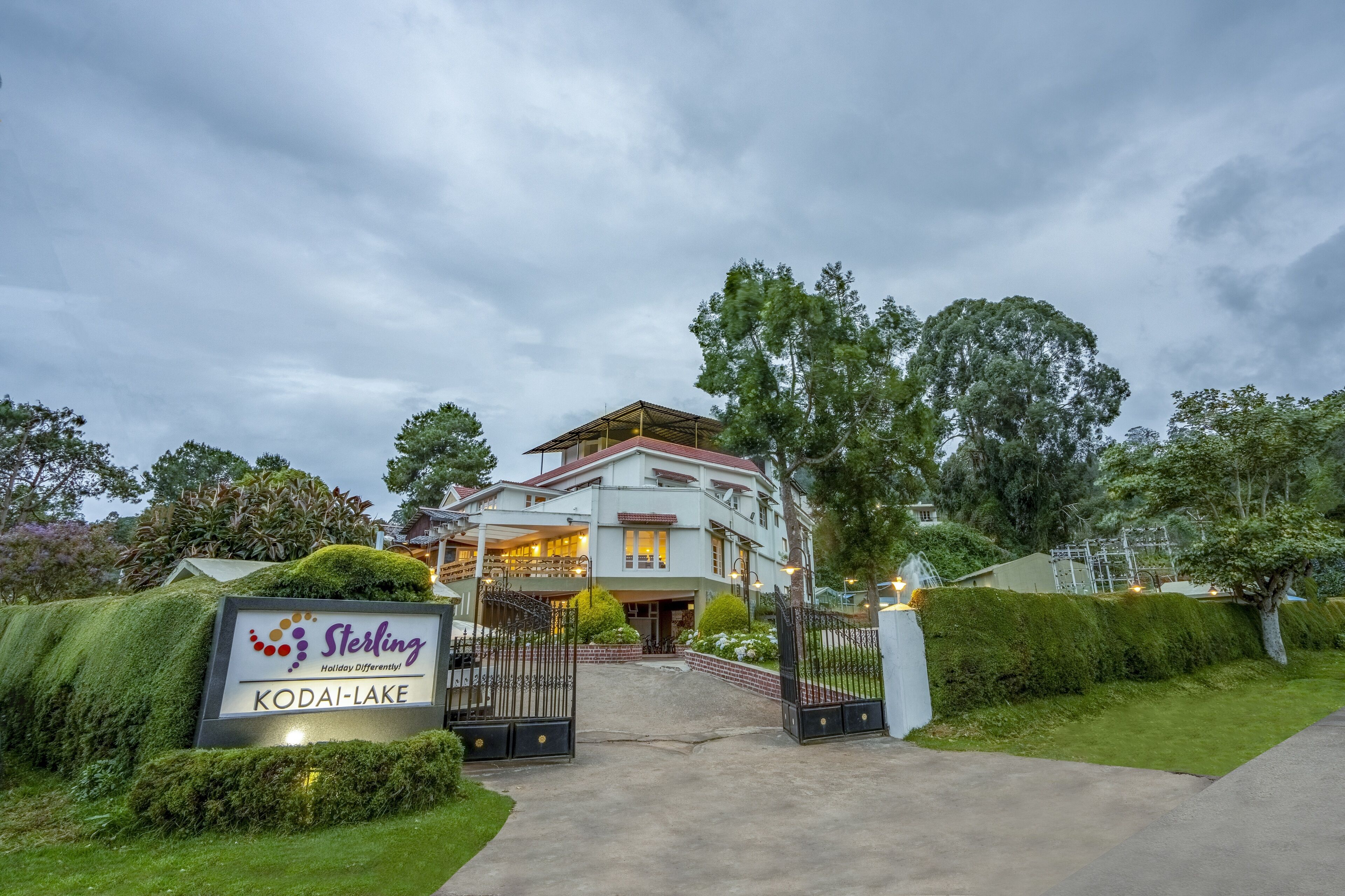 Un hotel grande de dos pisos con un letrero que dice “Sterling Holiday Differententi” y “Kodai-Lake”.