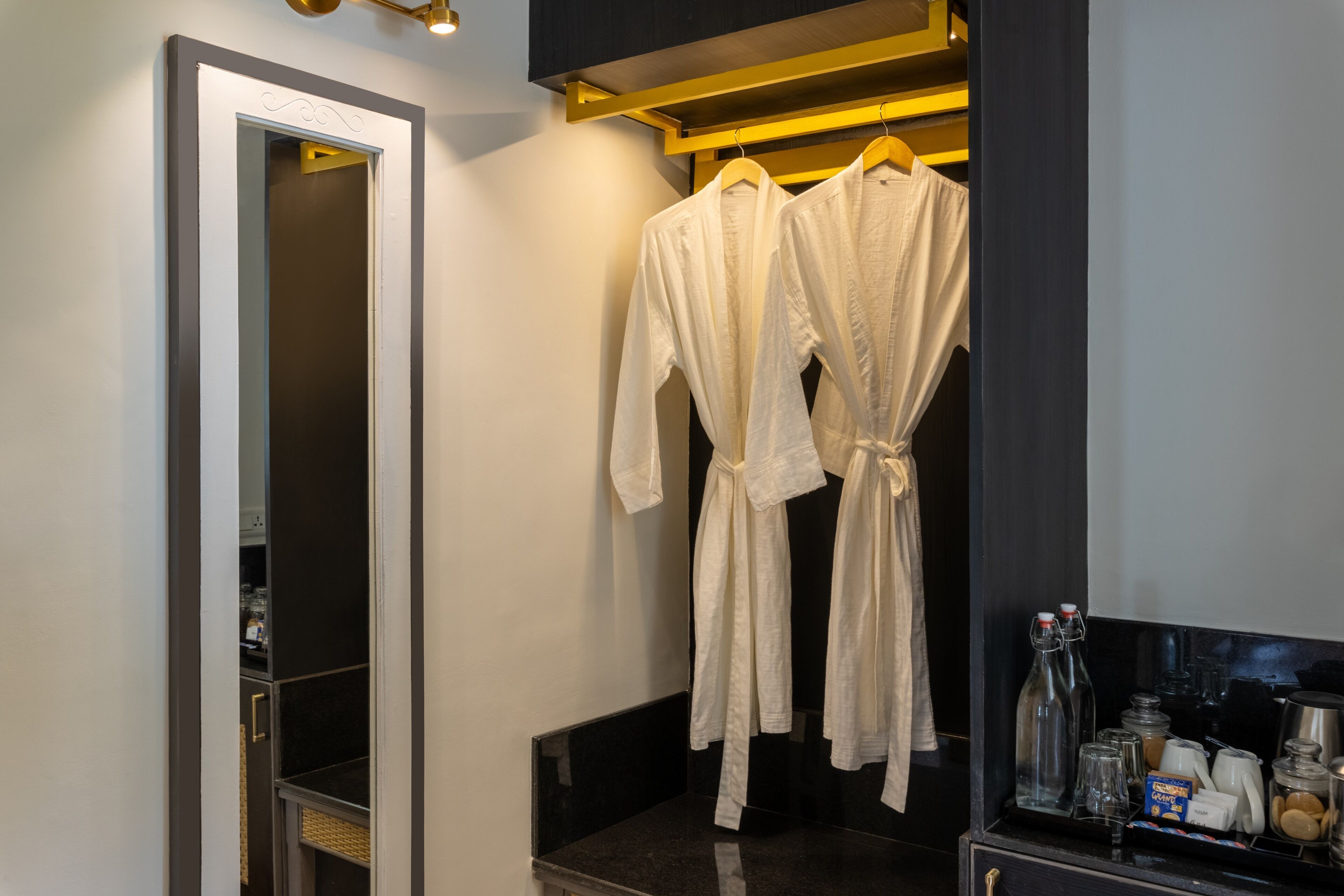 A modern bathroom with a mirror, robe hooks, and a vanity with toiletries.