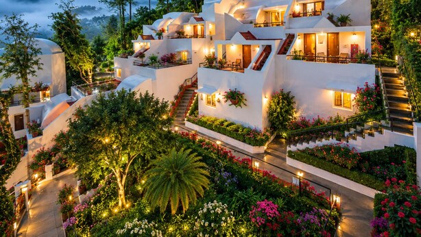 Un hôtel moderne à plusieurs niveaux, doté de terrasses extérieures, d’escaliers et d’une végétation luxuriante.
