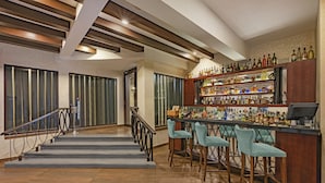Un espace bar avec un escalier, des tabourets de bar et une variété de bouteilles d’alcool.