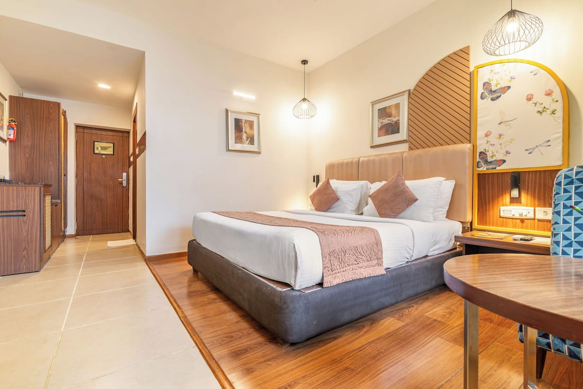 Une chambre d’hôtel moderne avec un grand lit, un plancher en bois, un bureau et un miroir fixé au mur.