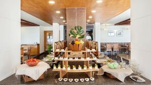 Un buffet composé de plusieurs tables de service, d’une plante décorative placée au centre et d’une grande variété de plats.
