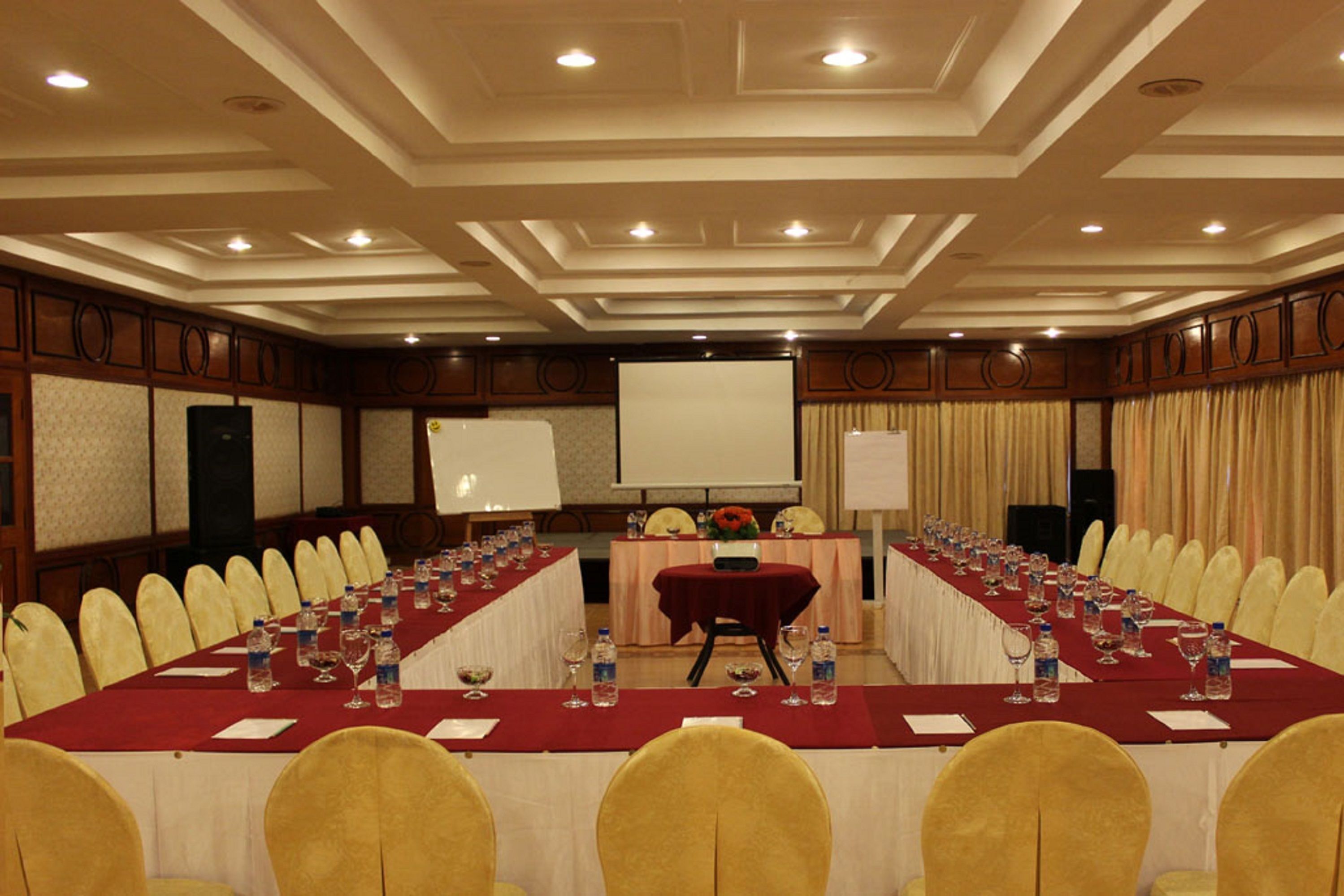 A conference room with a long table, yellow chairs, and a projector screen.