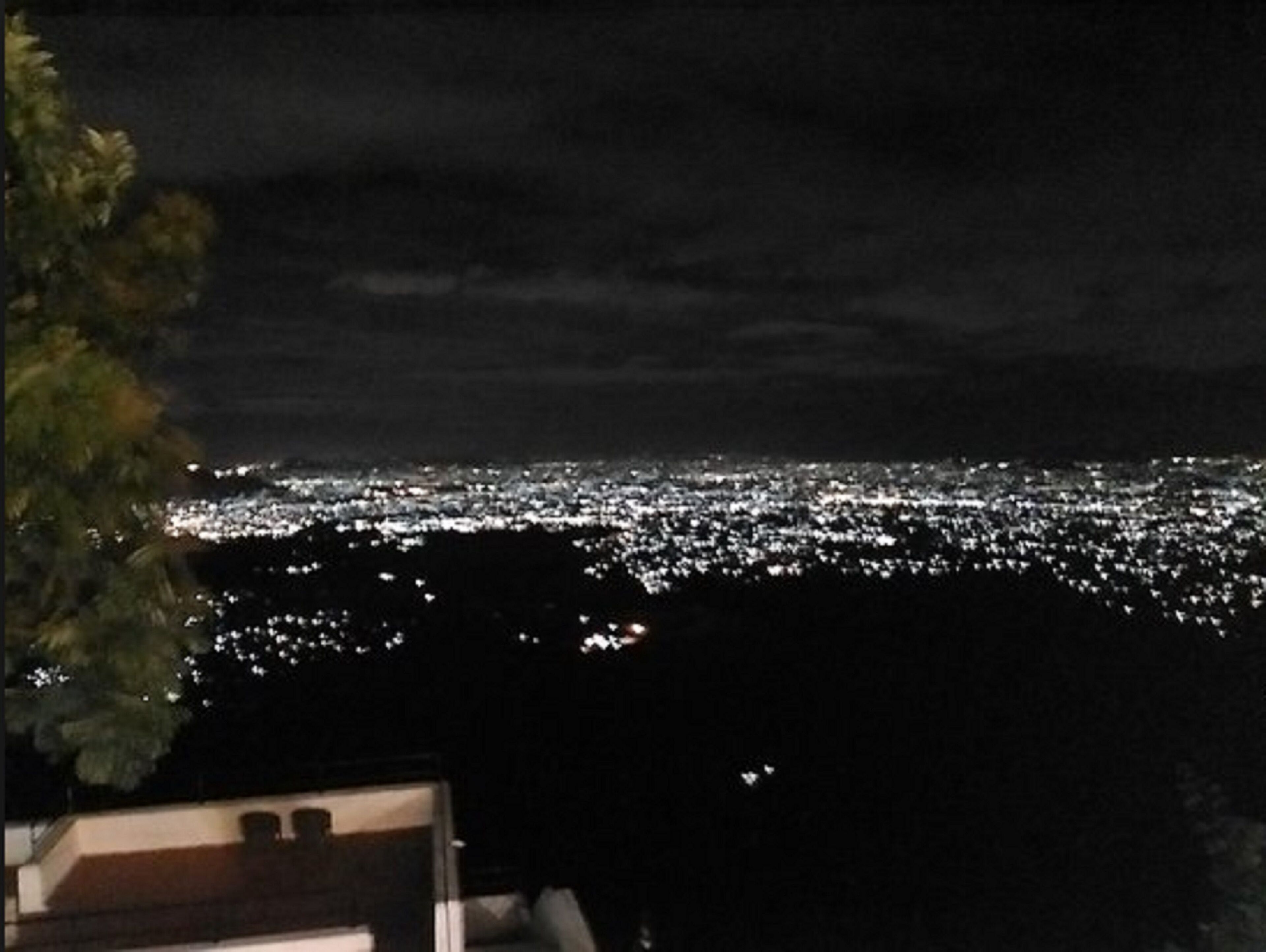 A nighttime view of a cityscape with a dense array of lights, likely from buildings and streets.