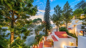 Un hôtel moderne à plusieurs étages, doté de terrasses extérieures et d’une végétation luxuriante.