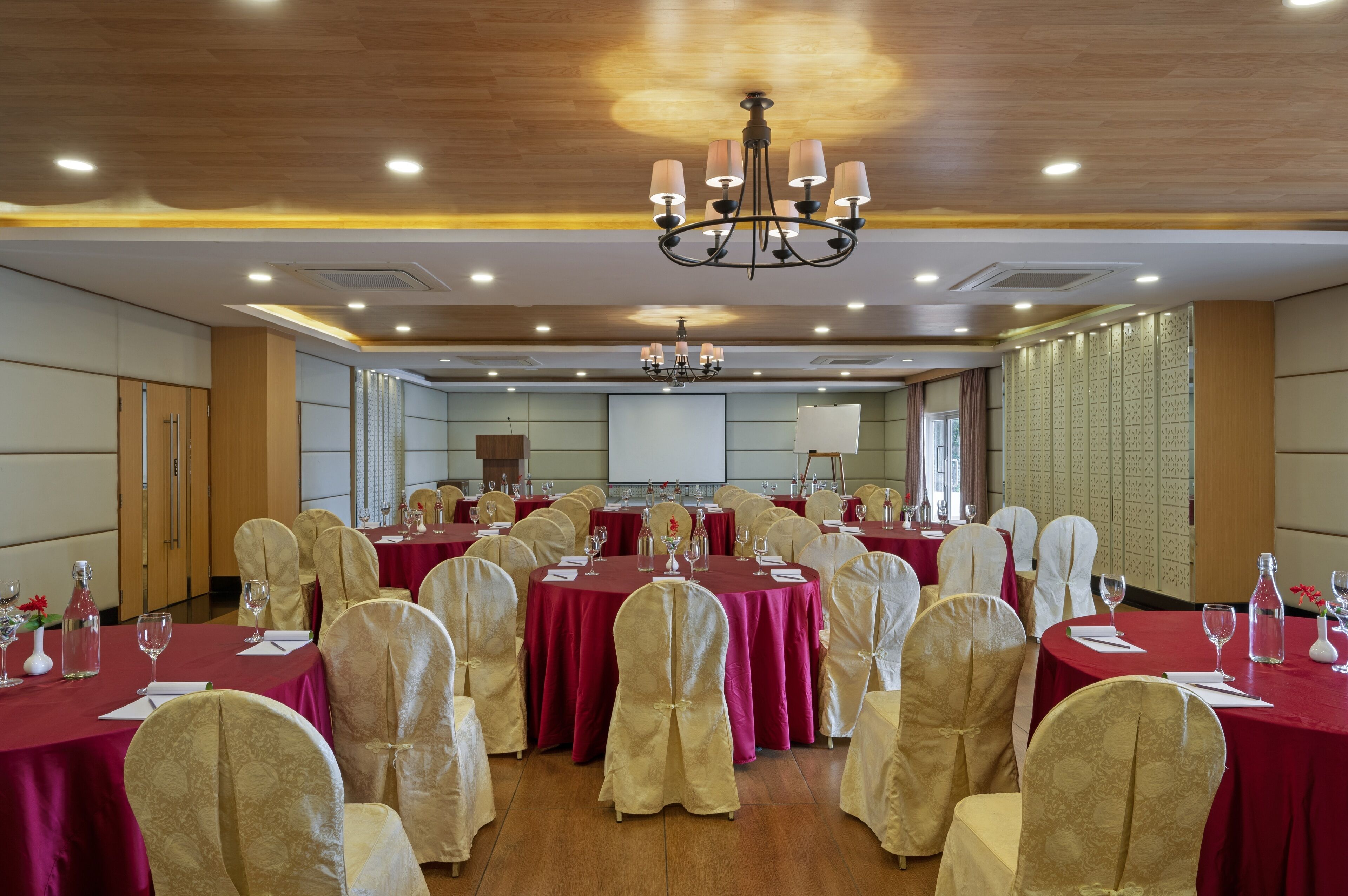 A conference room with round tables, chairs, and a projector screen.