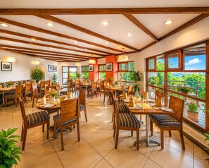 Un restaurant amb mobiliari de fusta, grans finestres i plantes en testos.