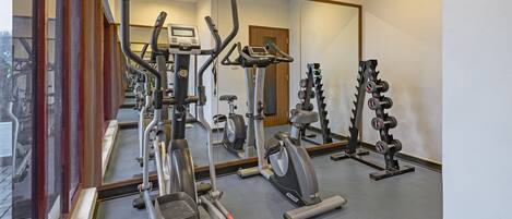 A gym with various exercise equipment, including treadmills, elliptical machines, and weightlifting stations.