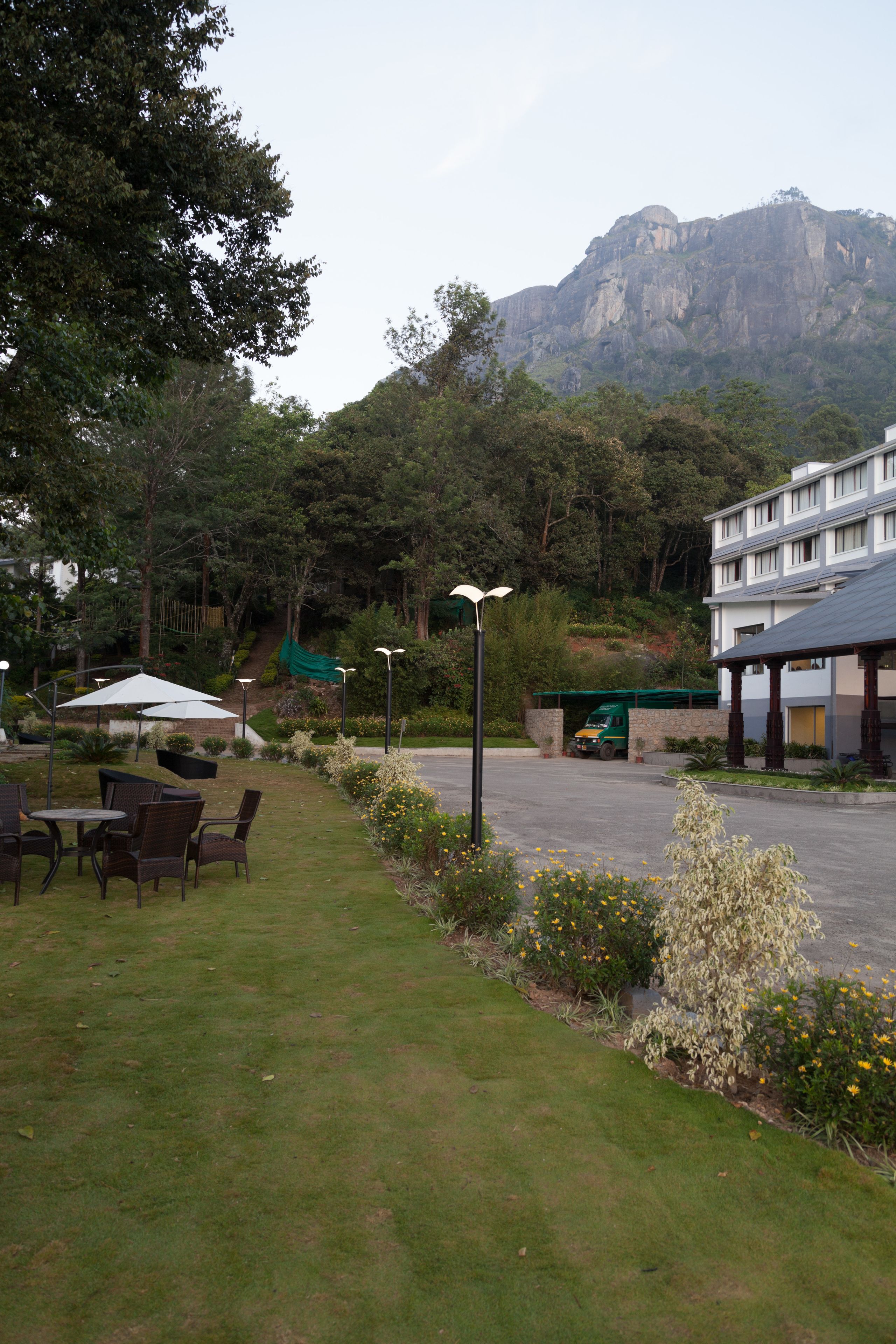 A hotel courtyard with outdoor seating, a parking area, and a mountain backdrop.