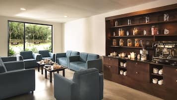 A modern living room with blue sofas, a coffee machine, and shelves with jars.
