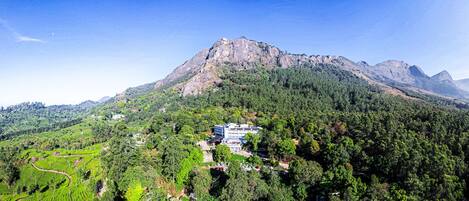 A mountainous landscape with a large building surrounded by lush greenery and terraced fields.