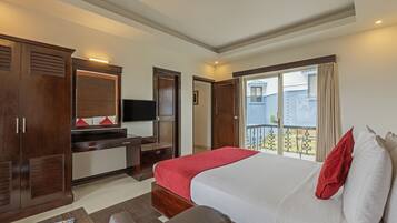 Habitación de hotel con una cama grande, un escritorio, un armario y un balcón con vistas.