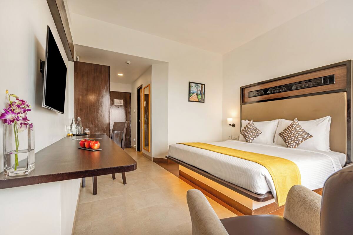 A hotel room with a bed, bedside table, and a TV mounted on the wall.