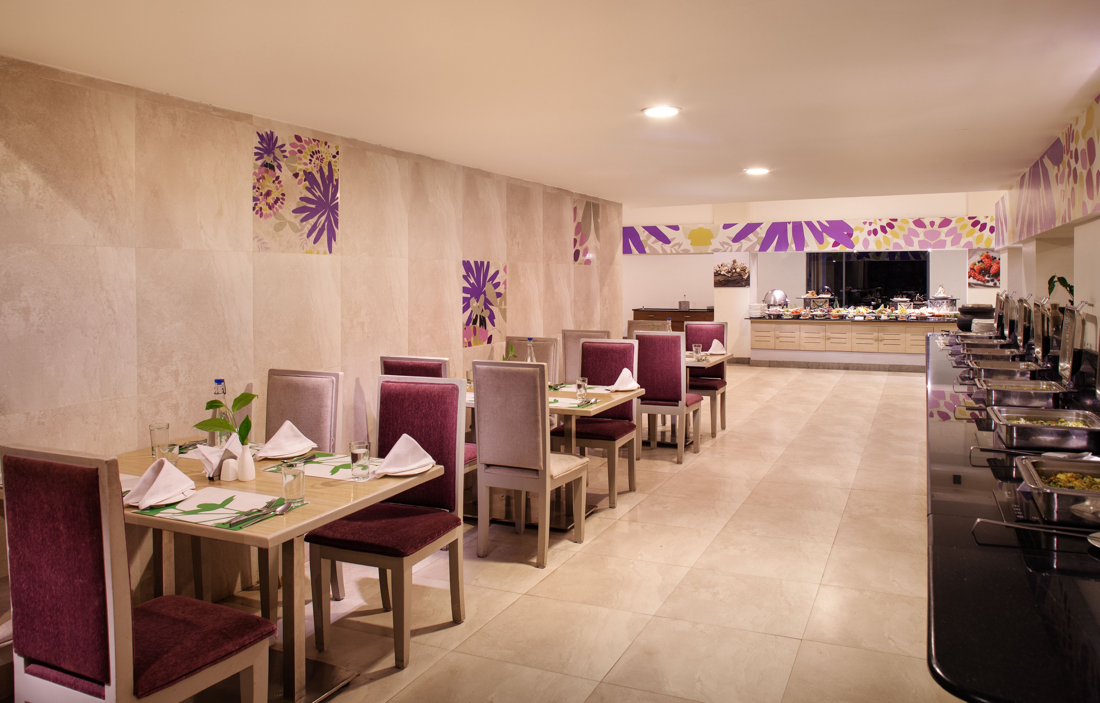 Un comedor con varias mesas y sillas, una barra de buffet y decoración en las paredes.