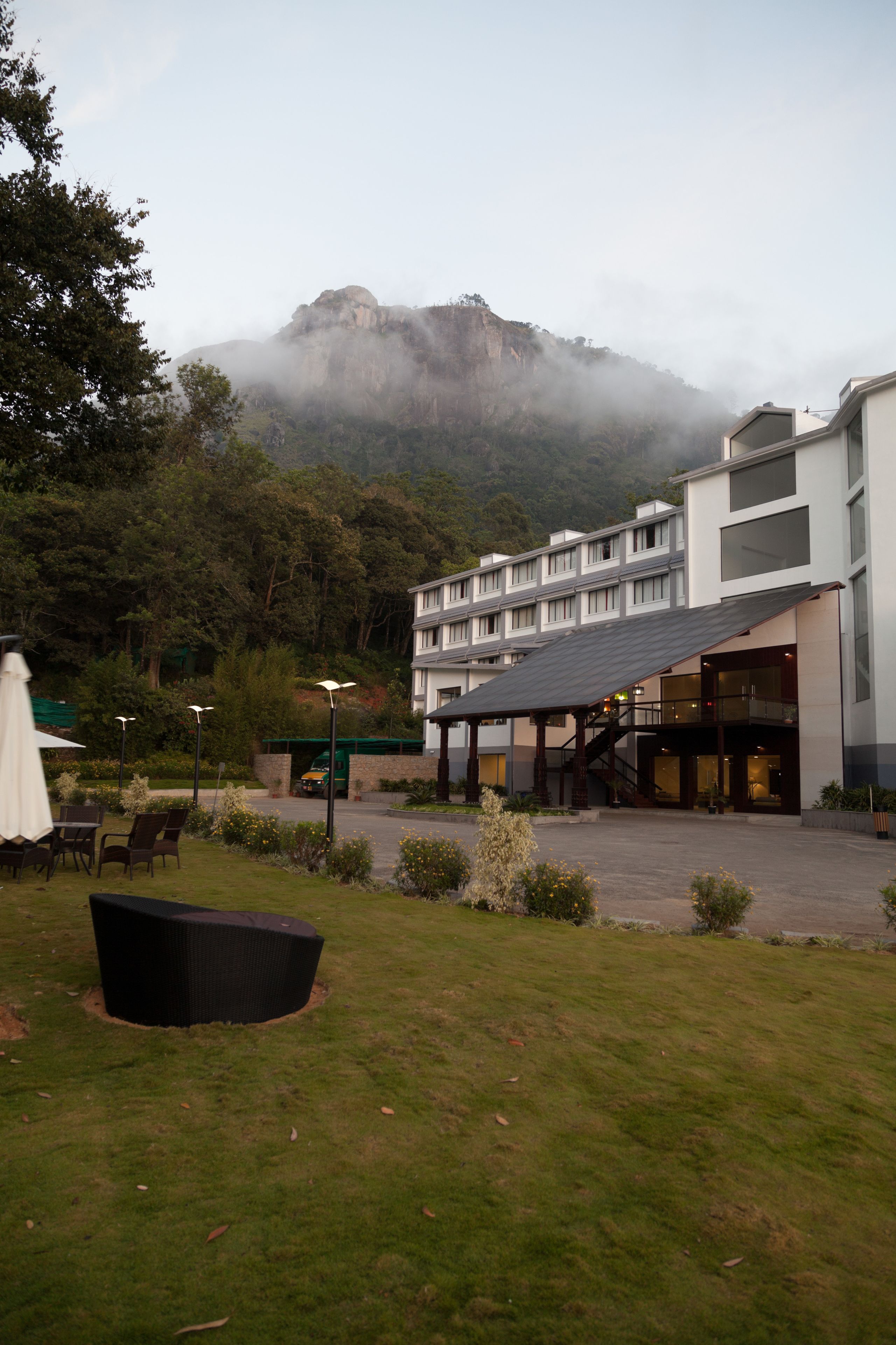 Ein Hotel mit modernem Design, mit einer überdachten Außenbereich-Sitzgelegenheit, einer Treppe zu den oberen Etagen und Blick auf einen Berg im Hintergrund.