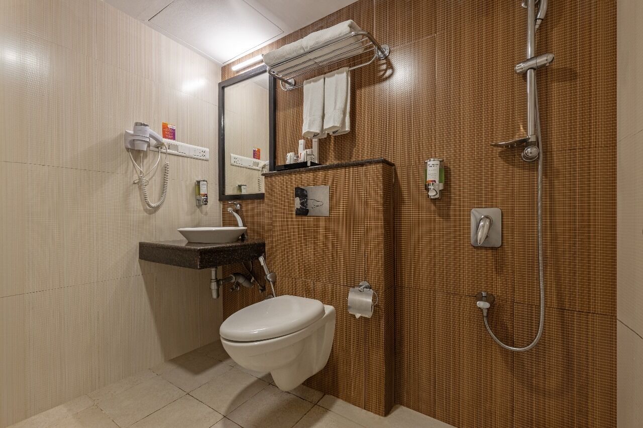 A bathroom with a toilet, sink, mirror, towel rack, and shower.