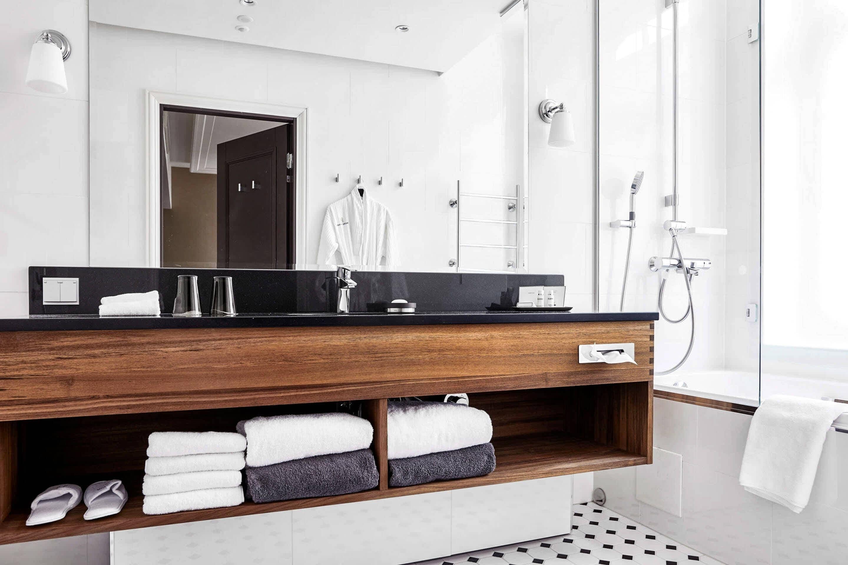 Un baño moderno con tocador de madera, un espejo grande y una cabina de ducha de vidrio.