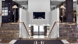 Un hall d’hôtel doté d’un escalier en marbre, d’une cheminée et d’un panneau indiquant l’emplacement des salles de réunion et de la salle de sport Havens.