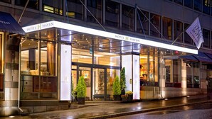 A modern hotel entrance with glass doors, potted plants, and a sign indicating the hotel name. - Hotel Haven (Helsinki)