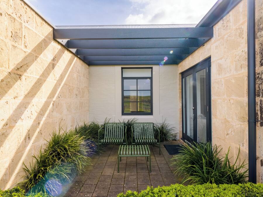 Un patio moderno al aire libre con un muro de piedra, una puerta de cristal y un banco.